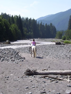 Tracy riding Echo on the rocky beach of the White River.